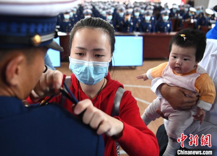 新消防員楊振的妻子彭莉與女兒現(xiàn)場見證丈夫加入“火焰藍(lán)”的神圣時(shí)刻?！⒅铱?攝